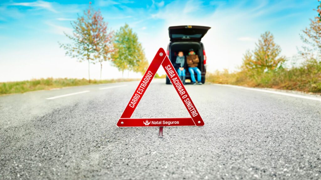 Triangulo de sinalização com as escritas "Carro quebrou? Saiba como acionar o sinistro"