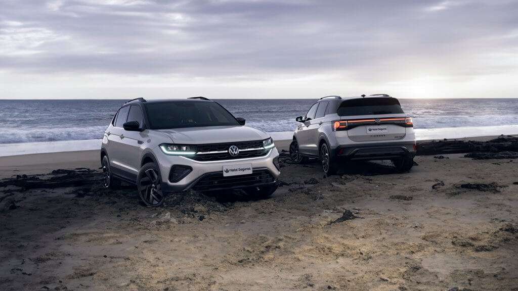 Imagem para o blog post sobre seguro do t-cross. A imagem mostra dois Volkswagen T-Cross 2025 estacionados em uma praia, com o mar ao fundo. O carro à esquerda está de frente, enquanto o da direita está de costas, ambos prateados e com placas "Natal Seguros." Na traseira do carro da direita, lê-se "T-Cross" e "250 TSI." A imagem destaca o design moderno e robusto dos T-Cross 2025 em um cenário natural e atraente, sugerindo uma combinação de estilo e aventura.