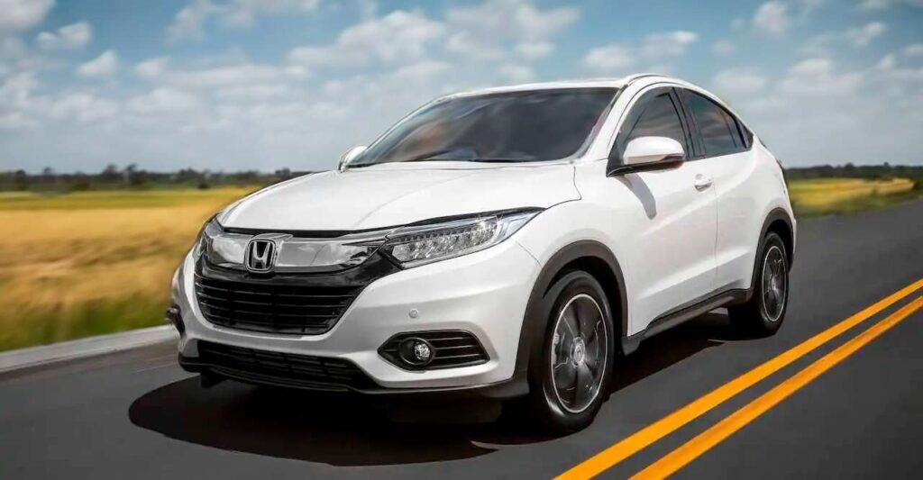 Imagem publicitária para o seguro HR-V. A imagem mostra um SUV Honda HR-V branco dirigindo em uma estrada, com o fundo desfocado indicando movimento. O veículo é o foco principal, com um design que apresenta linhas elegantes e um estilo moderno.