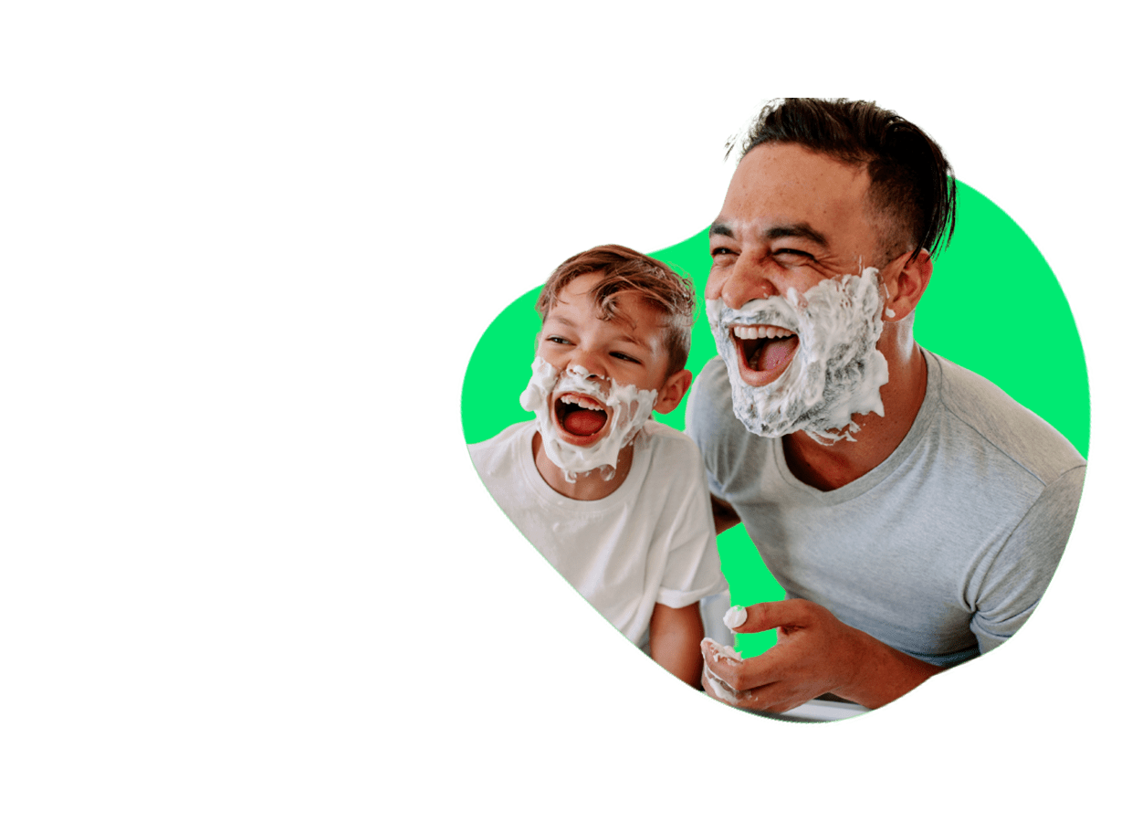 A imagem mostra um pai e filho fazendo a barba, com espuma de barbear no rosto. O fundo é verde. A imagem é para publicidade de seguro de vida.