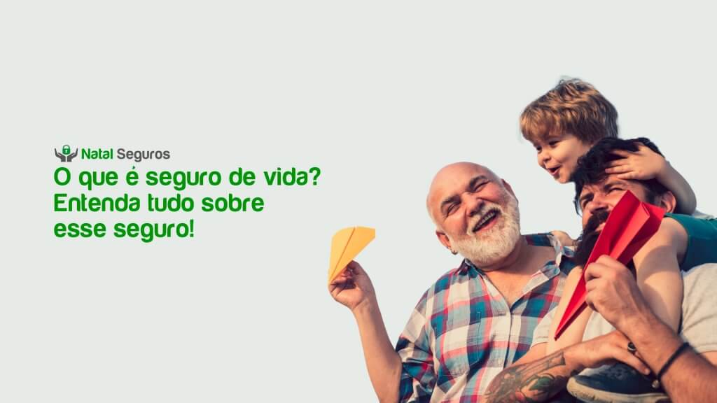 A imagem mostra três pessoas, um avô, pai e filho. Uma das pessoas parece estar segurando uma criança, enquanto a outra segura um objeto amarelo que se assemelha a um avião de papel. Ao fundo, há um céu claro. No lado esquerdo da imagem, há um texto em português que diz: “Natal Seguros - O que é seguro de vida? Entenda tudo sobre esse seguro!”