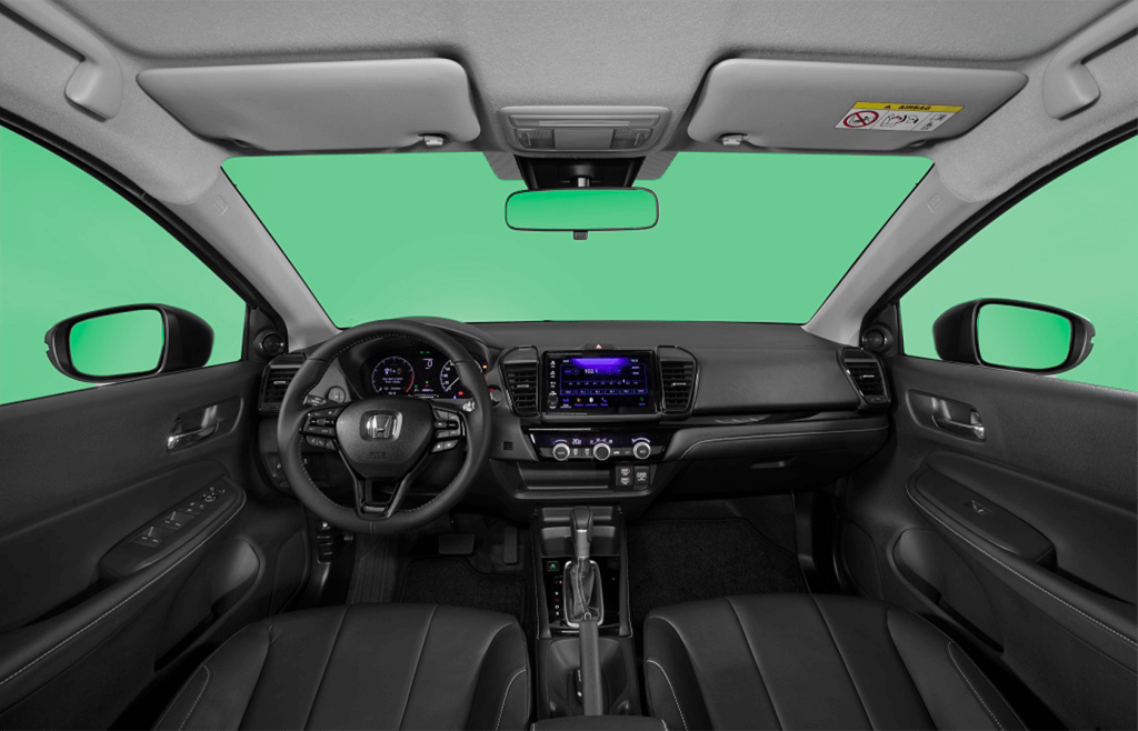 A imagem mostra o interior de um Honda City 2024. A foto é tirada da perspectiva do banco traseiro, focando no painel frontal e no volante. O volante possui o logotipo da Honda no centro e vários botões de controle. Atrás do volante, há um painel de instrumentos digital com mostradores iluminados. No centro do painel, há uma tela de infotainment com botões e controles abaixo dela. O console central inclui controles de ar-condicionado e uma alavanca de câmbio automática. Os bancos são de couro preto, e as portas têm acabamentos que combinam com o interior. O teto possui um espelho retrovisor e luzes de leitura. As janelas laterais e o para-brisa estão com um fundo verde, provavelmente para destacar o interior do veículo.