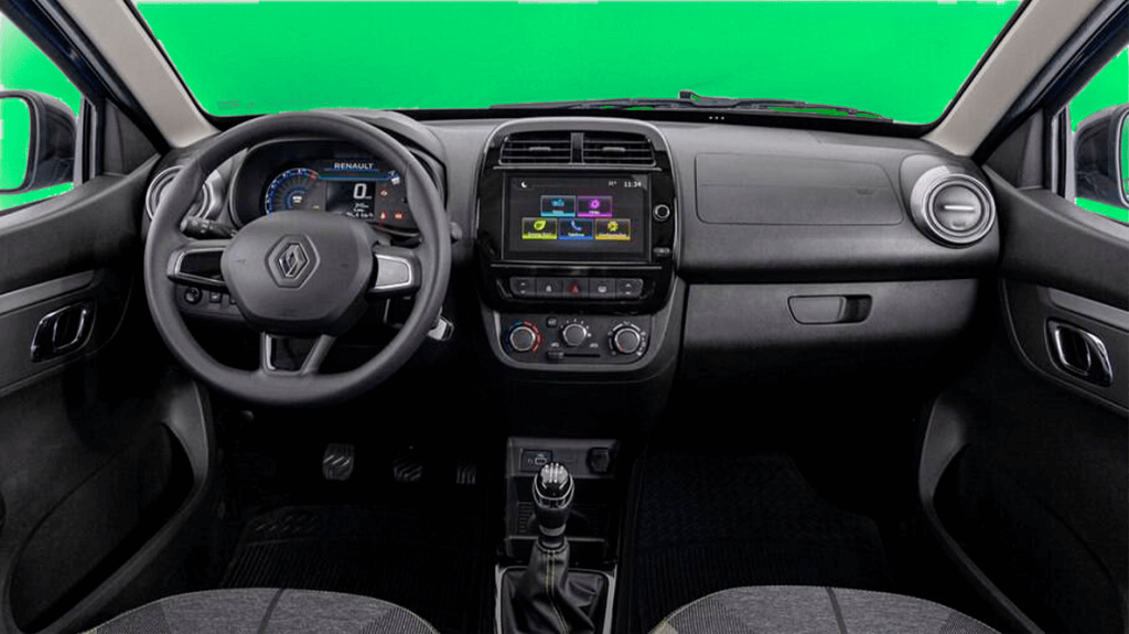 A imagem mostra o interior de um Renault Kwid. O painel de instrumentos está visível, com um volante ao centro que possui o logotipo da Renault. À esquerda do volante, há um painel digital que exibe informações como a velocidade (0 km/h) e o nome "RENAULT". No centro do painel, há uma tela de infotainment que exibe ícones coloridos para funções como telefone, música, navegação e configurações. Abaixo da tela, há controles manuais para o ar-condicionado e outras funções do carro. O câmbio manual está localizado na parte inferior central da imagem. O interior é predominantemente preto com detalhes em prata. Esta imagem ilustra o blog post sobre seguro kwid